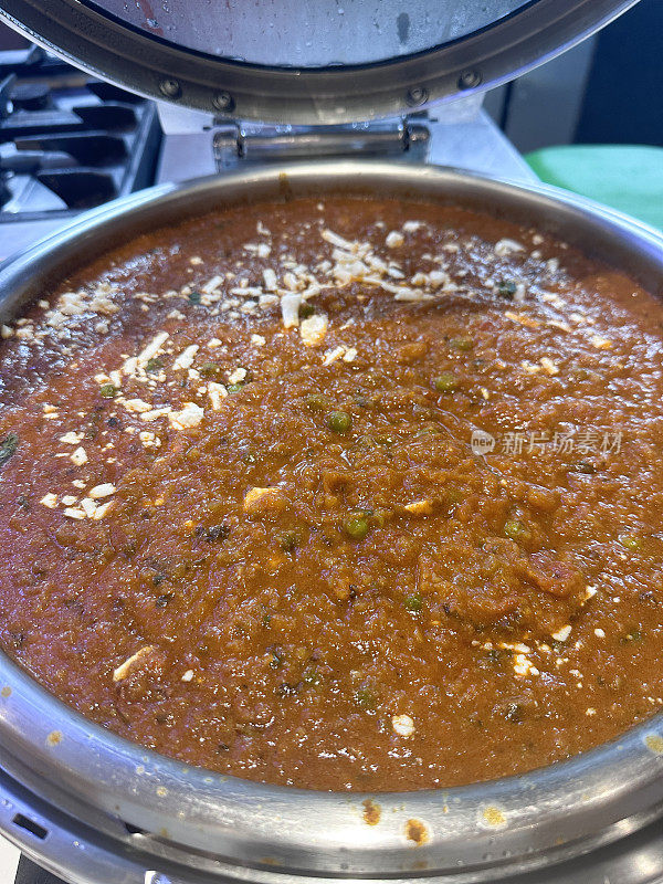 Pav bhaji(厚厚的蔬菜咖喱)在开盖的不锈钢餐盘中的特写图像，在酒店自助服务自助餐中提供的流行快餐菜肴，高架视图